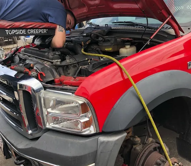 Engine work on a Ford Super Duty from a topside creeper
