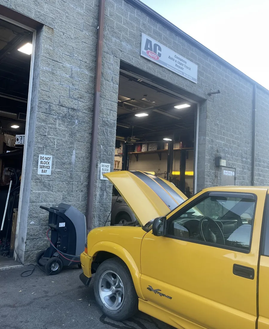 Yellow Chevy S10 outside the shop with the hood up